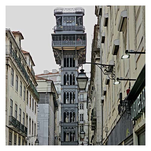 Ein schmiedeeiserner Turm ragt sechs Stockwerke nach oben. Oben ist eine Plattform mit Brüstung. In dem Turm fährt ein Fahrstuhl, um Menschen von der Unter- in die Oberstadt zu bringen.