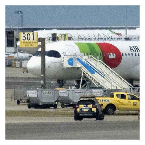 Flugzeug mit Treppe für Passagiere auf Flughafen. Davor stehen leere Container, wahrscheinlich für Koffer.